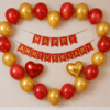 Red and Gold Heart Shape Happy Anniversary Decoration Heart shape Happy Anniversary decoration with red and golden balloons, red and gold cardstock anniversary banner, and red and golden heart foil balloons on a wall backdrop.