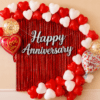 Red and white heart balloon anniversary decoration with red foil curtain, silver Happy Anniversary banner, love you foil balloons and golden confetti balloons.