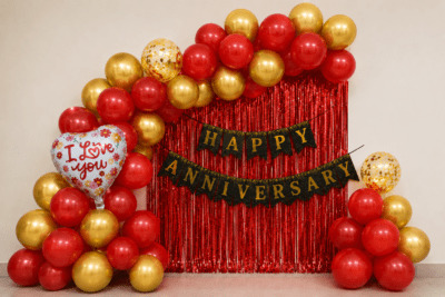 Red & Gold Happy Anniversary Balloon Decoration with Love You Foil Balloons Red and gold Happy Anniversary balloon decoration with black gold banner, love you foil balloons and golden confetti balloons for anniversary party setup.