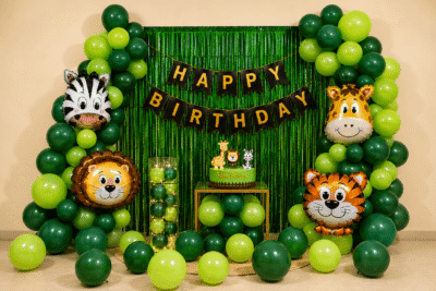 Jungle safari theme happy birthday decoration with green balloons, animal foil balloons, fringe curtain and birthday banner for kids party setup.