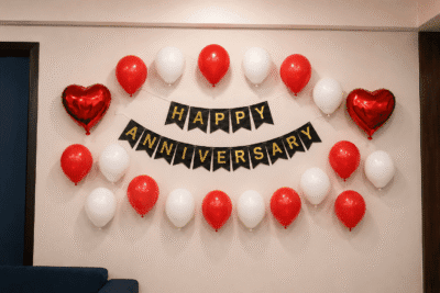 Red & White Happy Anniversary Balloon Decoration Red and white Happy Anniversary wall decoration with black and gold cardstock banner, 20 balloons and two red heart foil balloons for anniversary celebration.