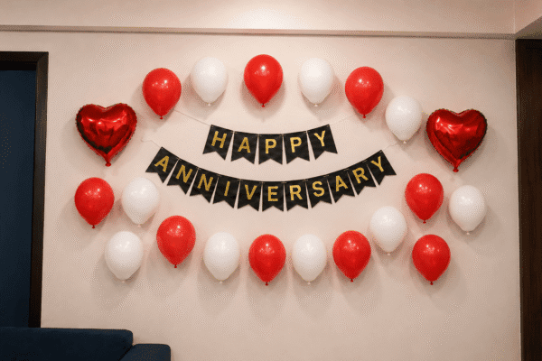 Red & White Happy Anniversary Balloon Decoration Red and white Happy Anniversary wall decoration with black and gold cardstock banner, 20 balloons and two red heart foil balloons for anniversary celebration.